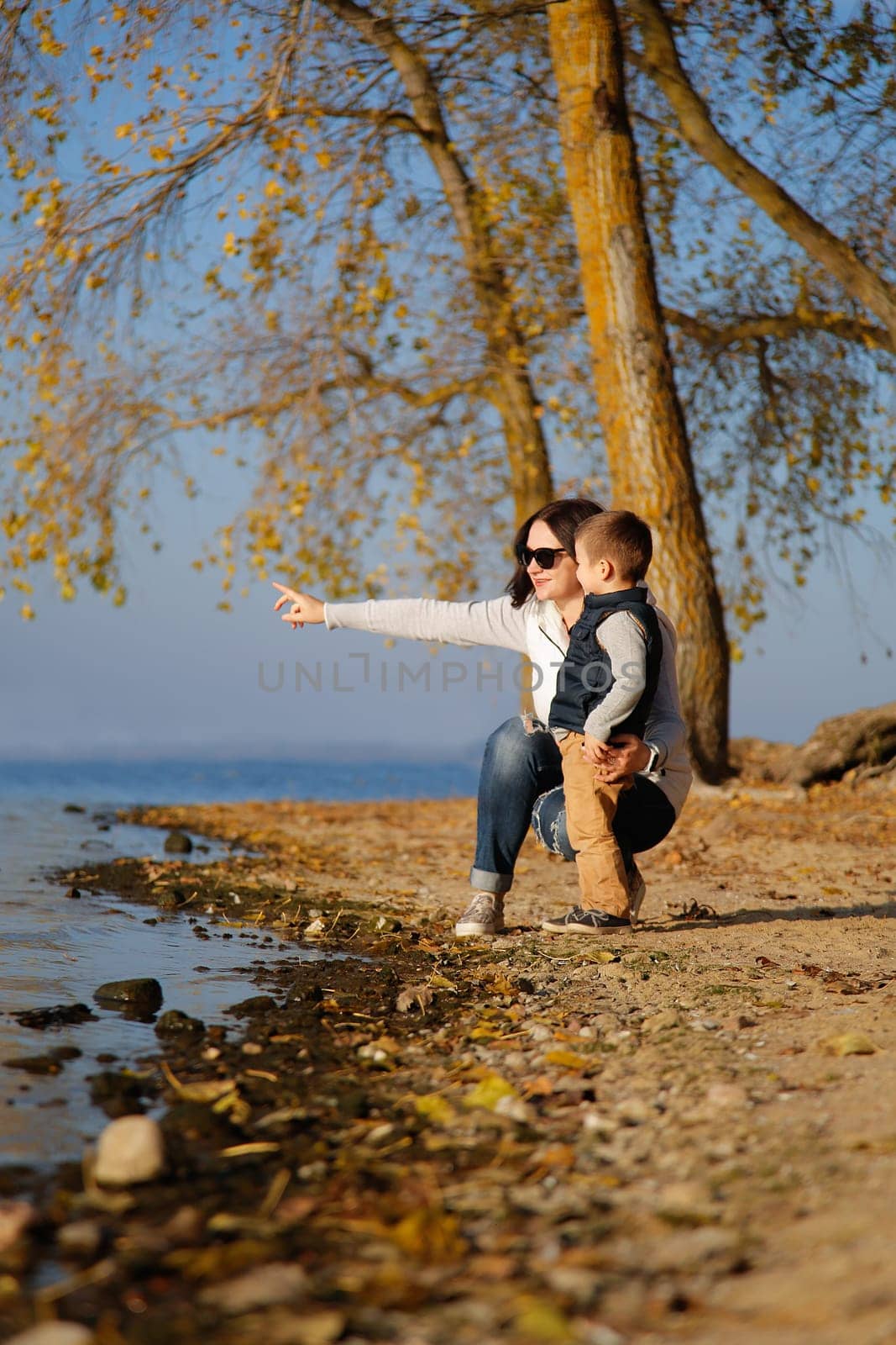 A mother and her young son joyfully pointing toward the shimmering water, embraced by natures peaceful tranquility