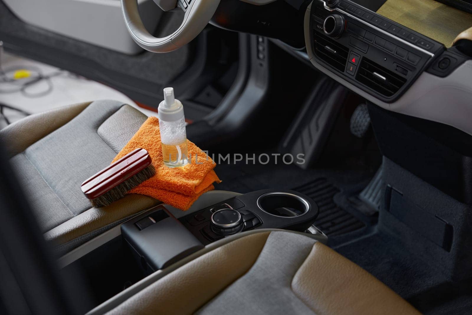 Cleansing tools. Brush towel and detergent in disinfectant spray bottle on front passenger seat high angle view closeup. Car detailing concept
