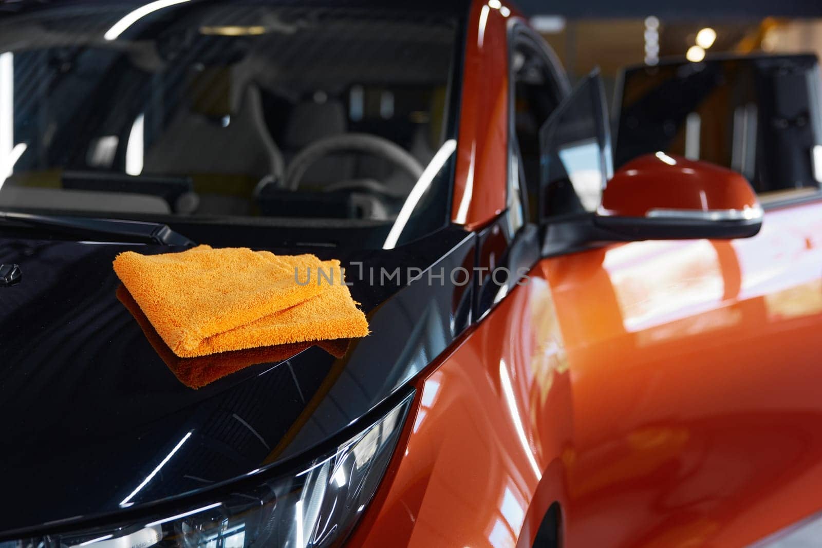 Microfiber towel cloth on shiny glossy surface of polished car. Professional auto service providing high quality cleansing routine procedure for luxury automobile