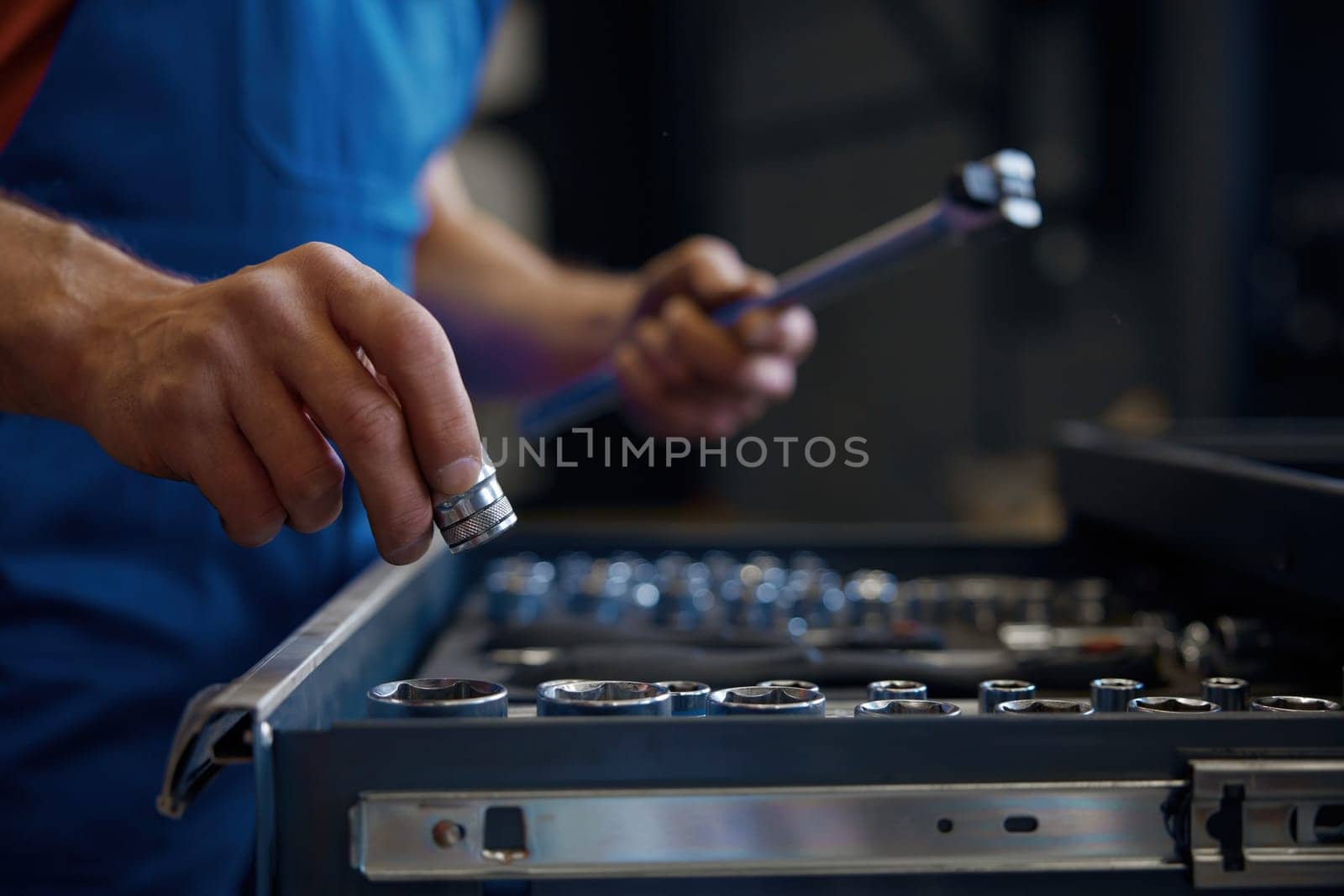 Crop shot of tool box and male mechanic hands taking wrench for work. Professional repairman service at auto garage