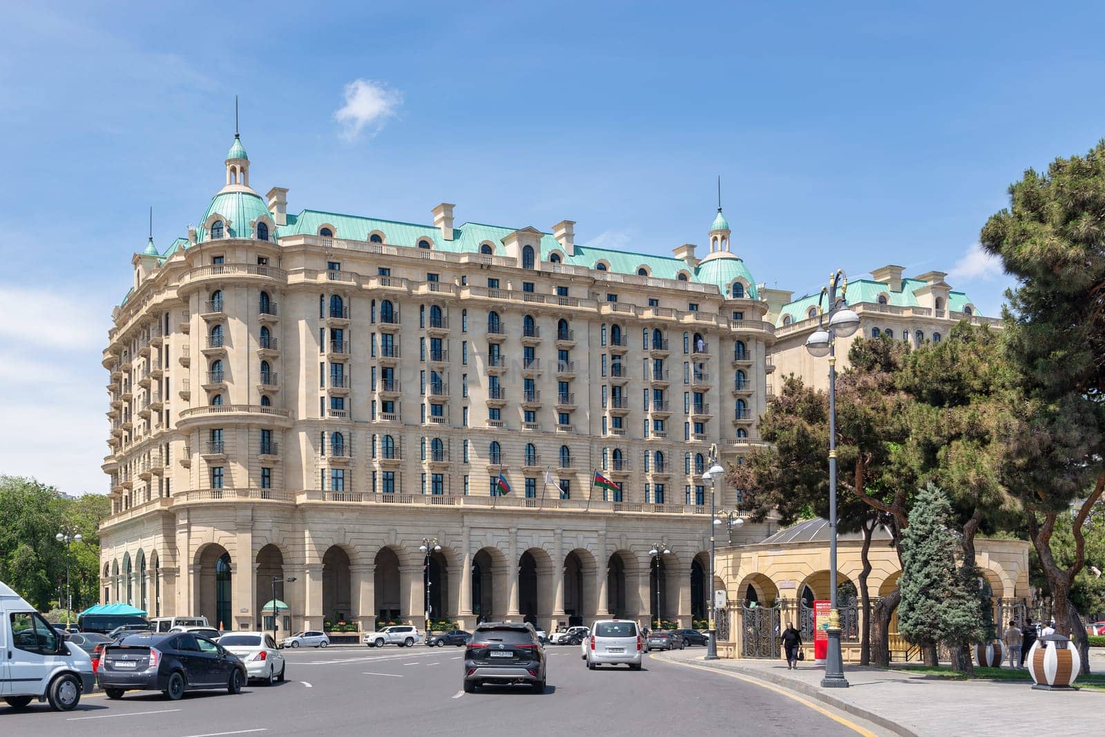 Baku, Azerbaijan - May 10, 2024: Beaux-Arts style Four Seasons Hotel stands on Neftchiler Avenue street. The building features a symmetrical facade with multiple stories, arched windows, and domes