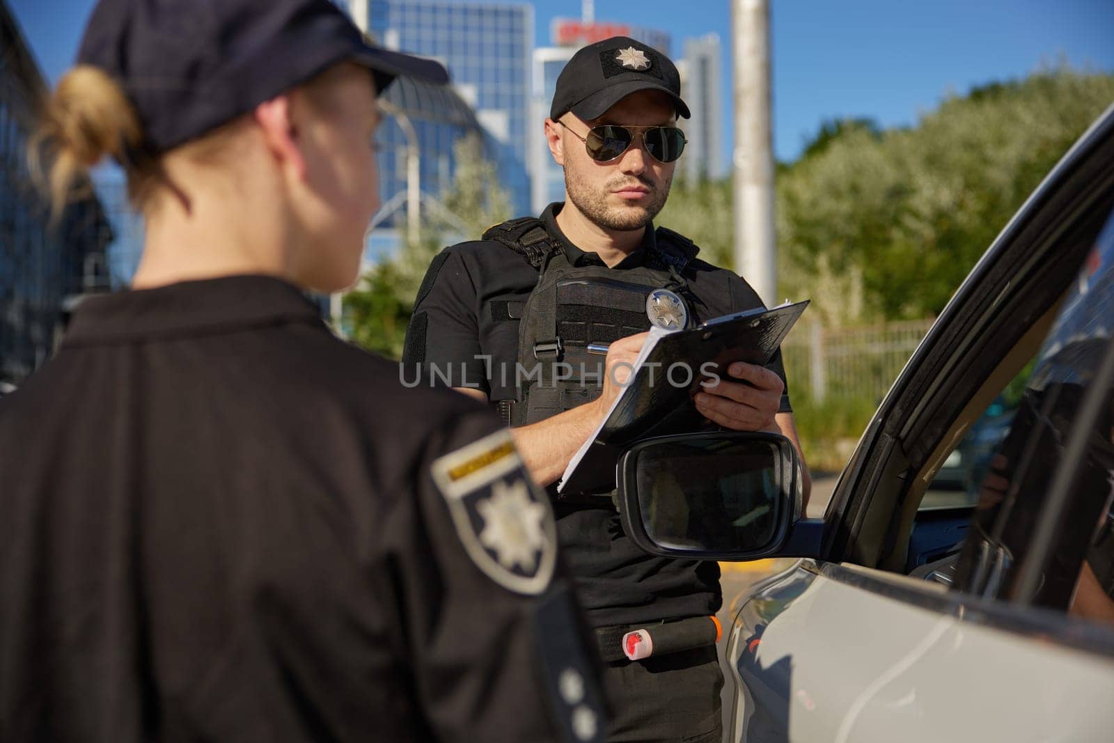 Police officers writing traffic ticket for parking violation. Street safety surveillance team at work