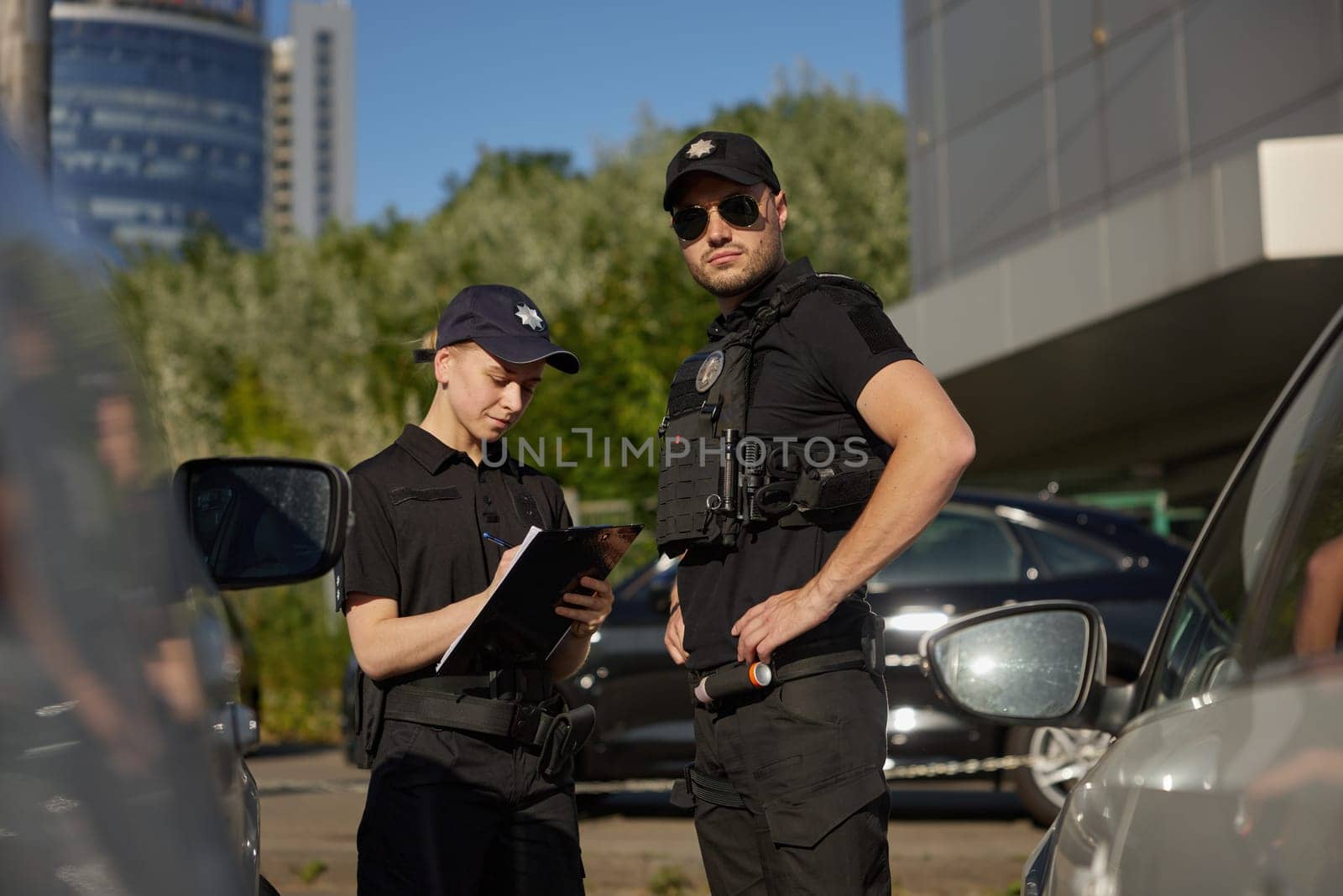 Patrol police team working on city street with parked cars. Police officers at work on street. Street safety surveillance team at work