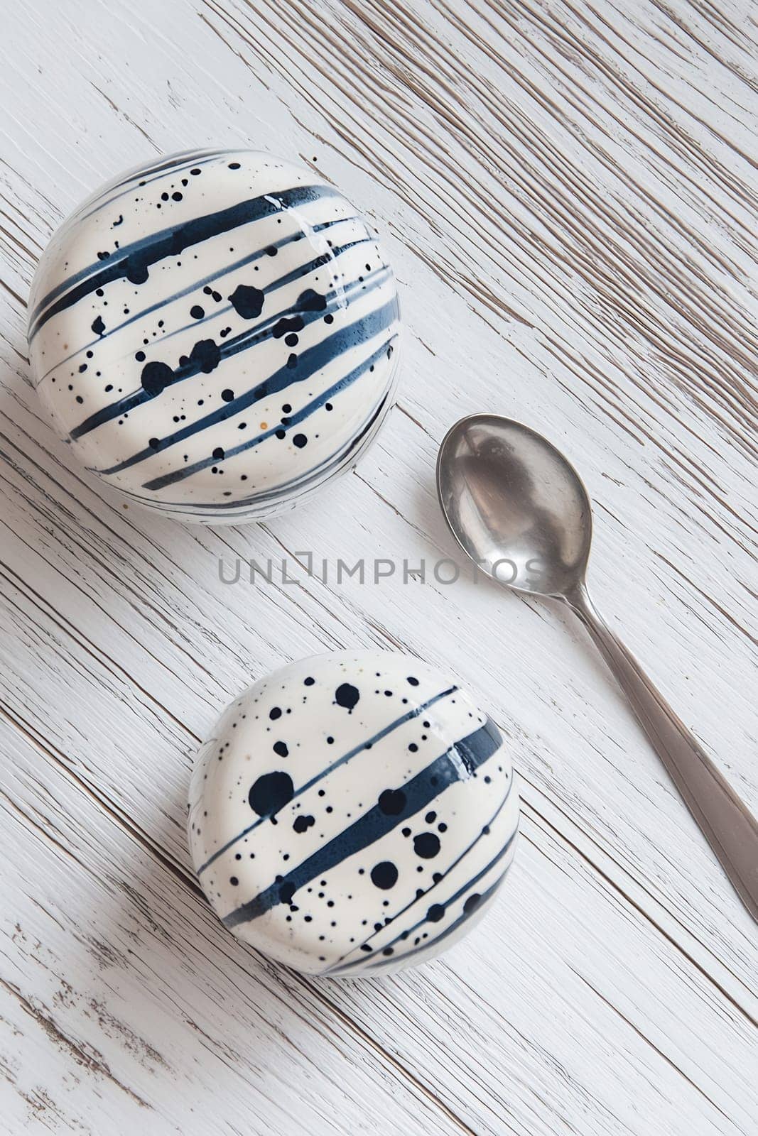 Two elegant dessert bowls with navy blue designs sit beside a silver spoon on a rustic wooden table.