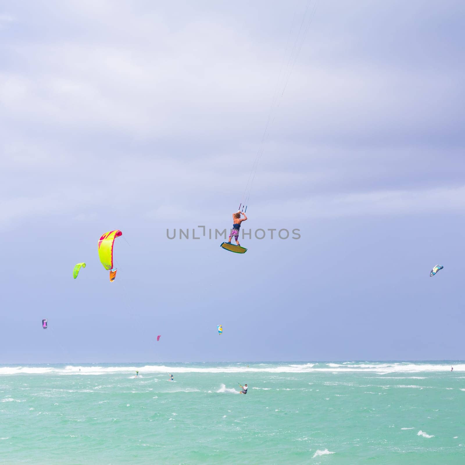 Kiteboarding. Fun in the ocean. Extreme Sport Kitesurfing. Kitesurfer jumping high in the air performing triks during kitesurfing session