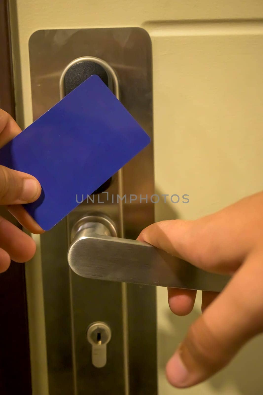 A hand holding a blue card key close to a hotel door lock, key electronic lock, hotel room, holidays in mallorca, spain