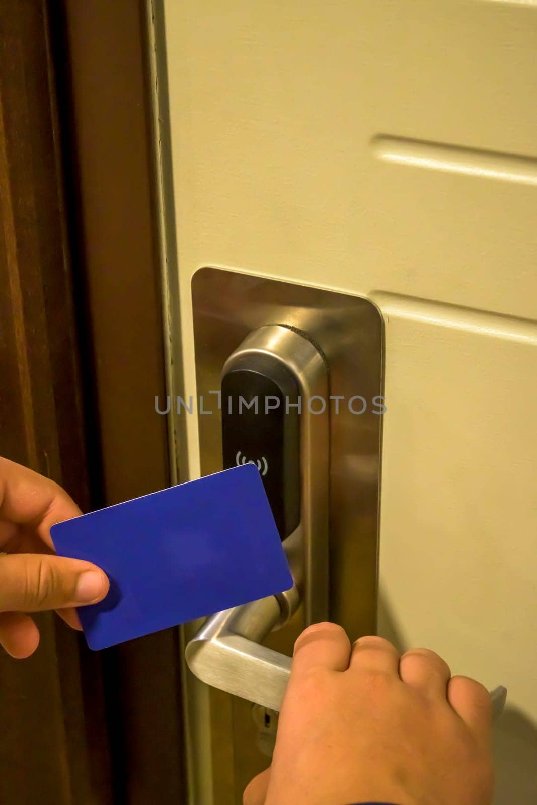 A hand holding a blue card key near a hotel door lock in a long hallway, key electronic lock, hotel room, holidays in mallorca, spain
