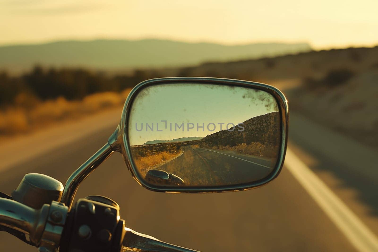 Open road reflecting in a motorcycle rearview mirror during a scenic sunset ride