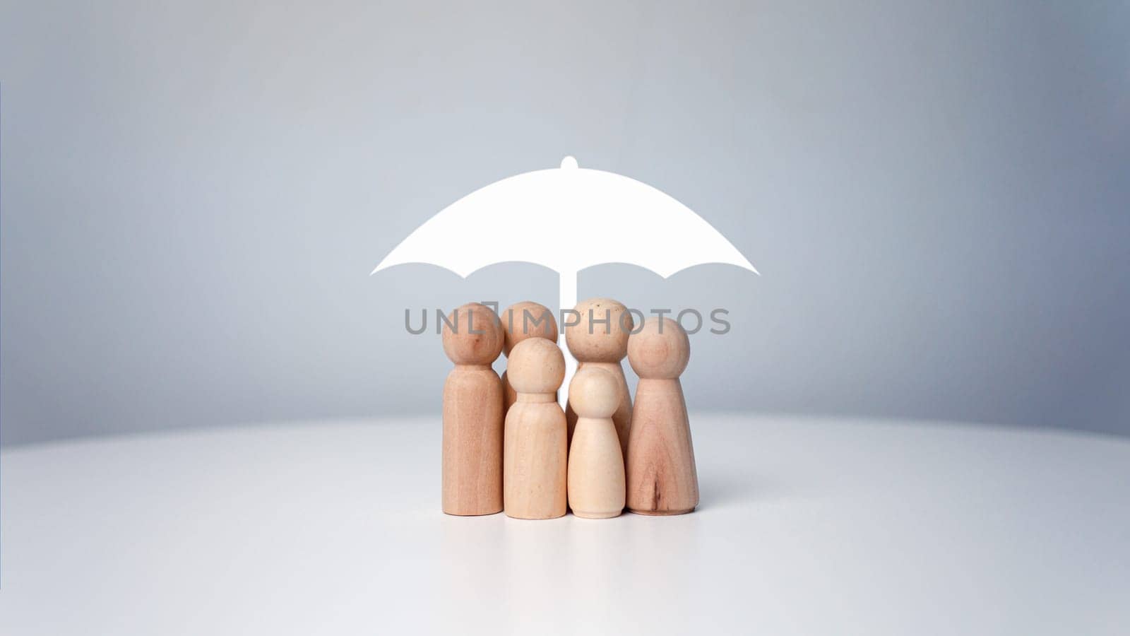 Protect and care for your family, umbrella above a family cover and shelter wooden people, security, protection, Finance or insurance concept, People lifestyles and Relationships in love concept.