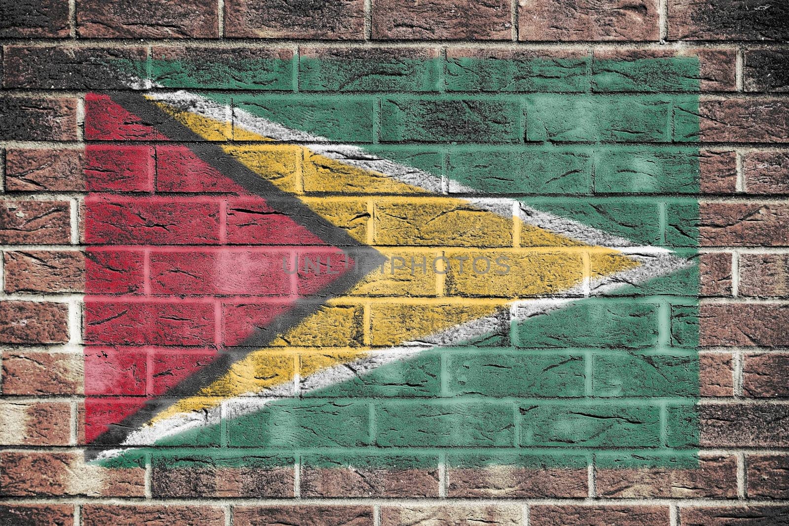 A Guyana flag painted on brick wall background red yellow green star black