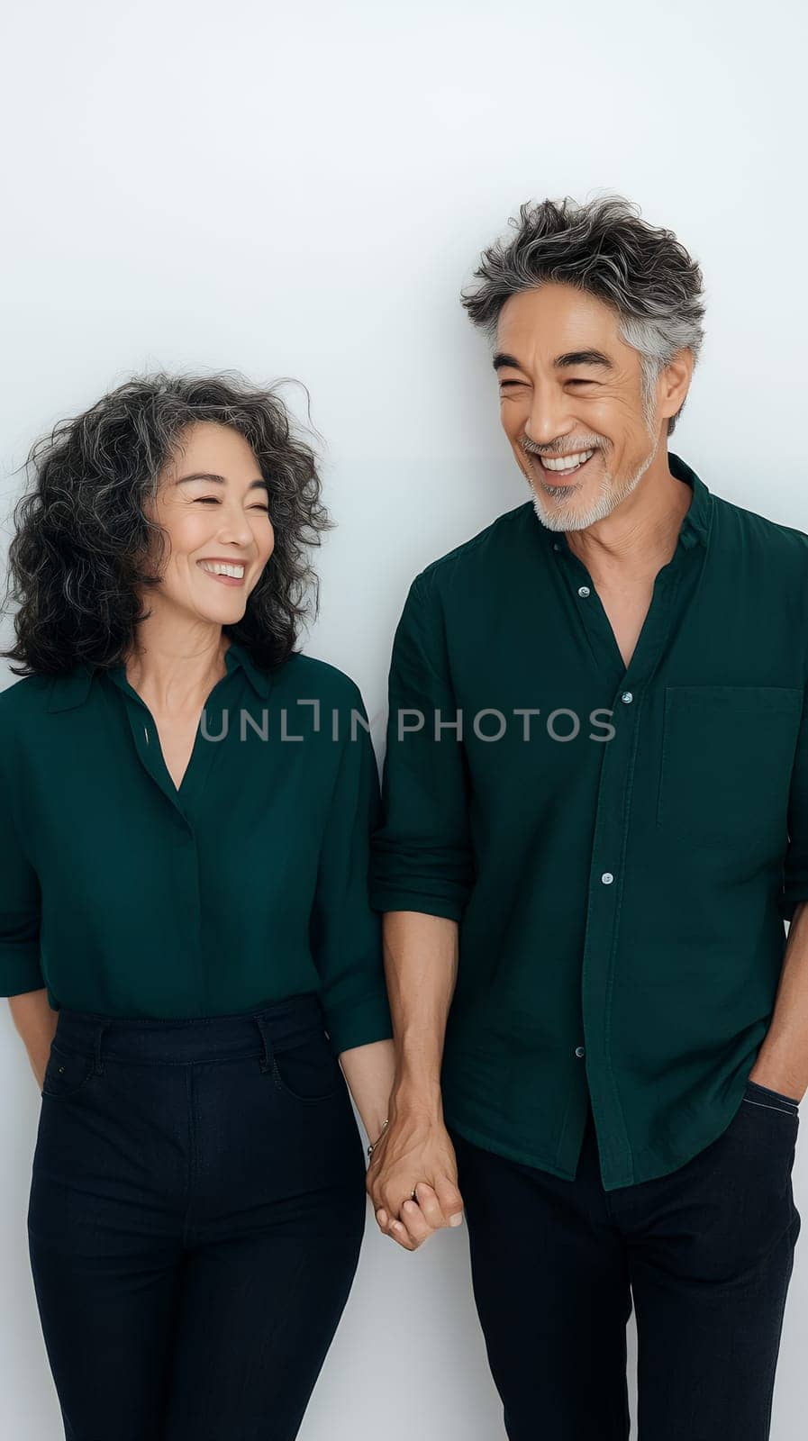 A joyful senior couple holding hands and smiling, expressing love and companionship against a light background.