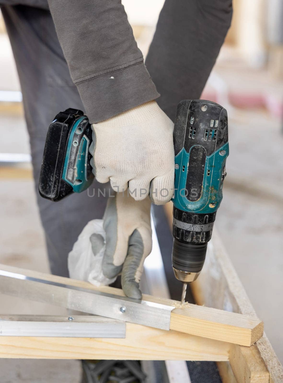 Carpenter working on wooden board to produce construction material or wooden furniture. Craftman using professional electric cordless drill. DIY concept