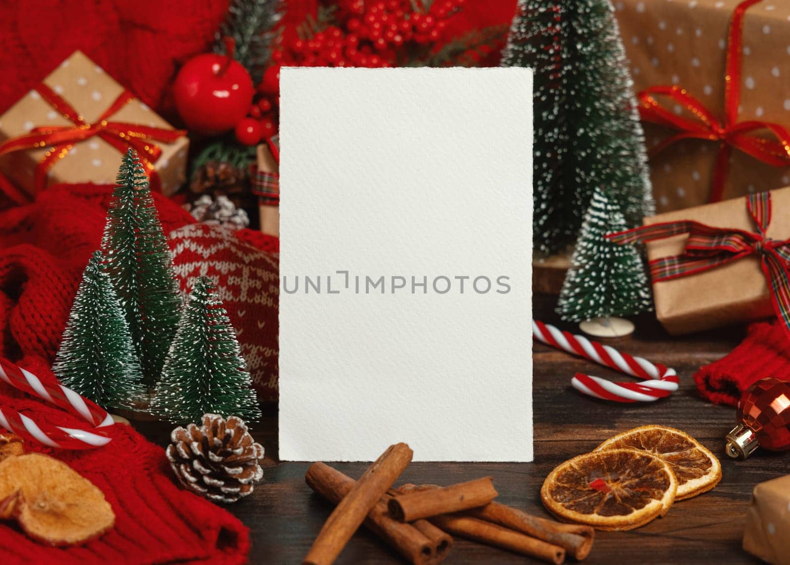 Greeting card near Christmas decor, trees, spices and red knitted sweater on dark wooden table closeup, place for text. Winter atmospheric mock up, family holiday time