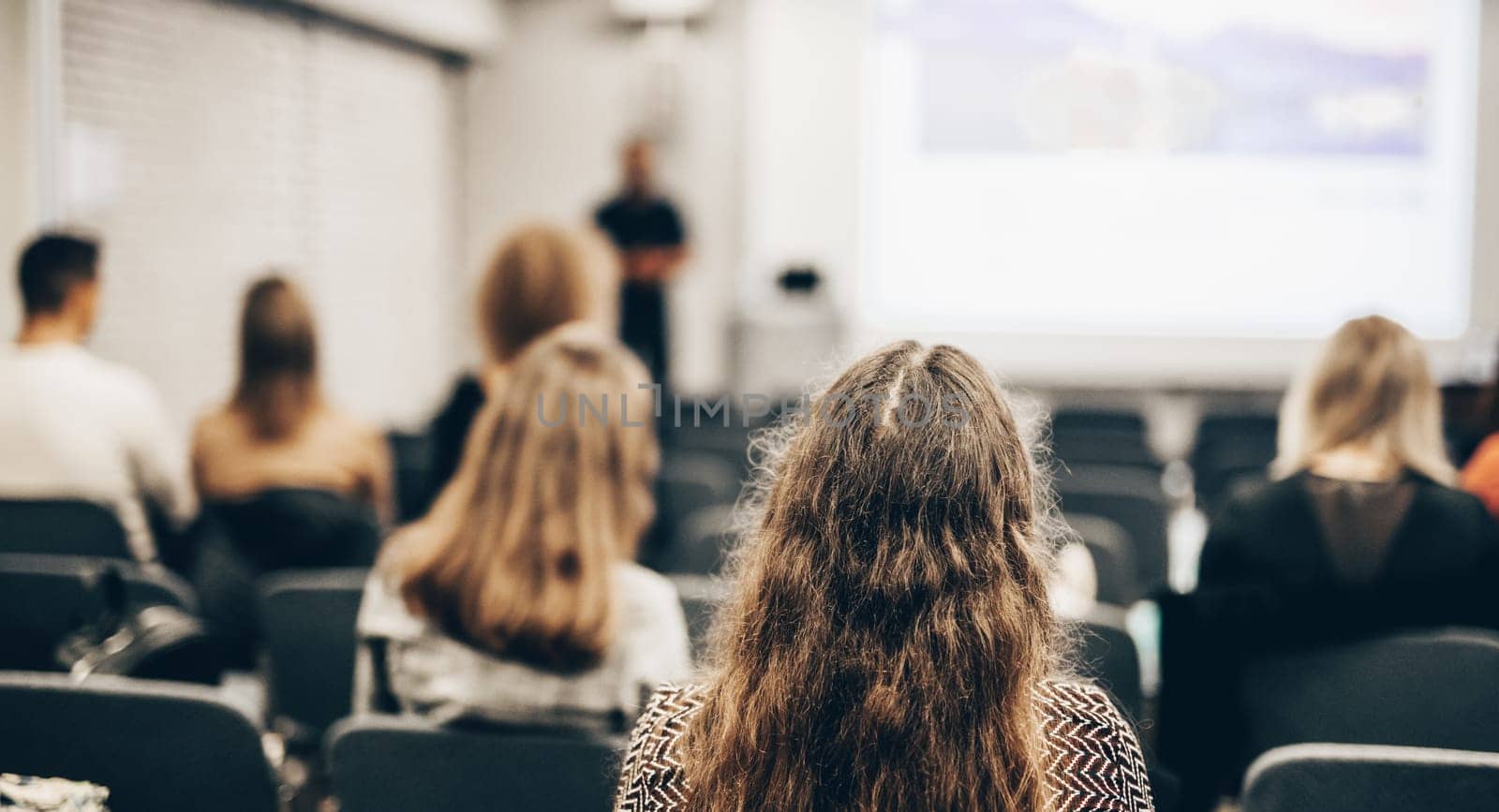 Speaker giving a talk in conference hall at business event. Rear view of unrecognizable people in audience at the conference hall. Business and entrepreneurship concept