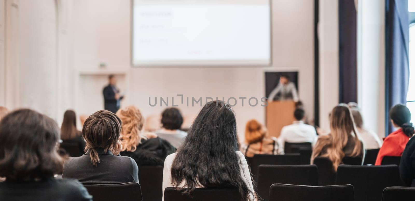 Speaker giving a talk in conference hall at business event. Rear view of unrecognizable people in audience at the conference hall. Business and entrepreneurship concept