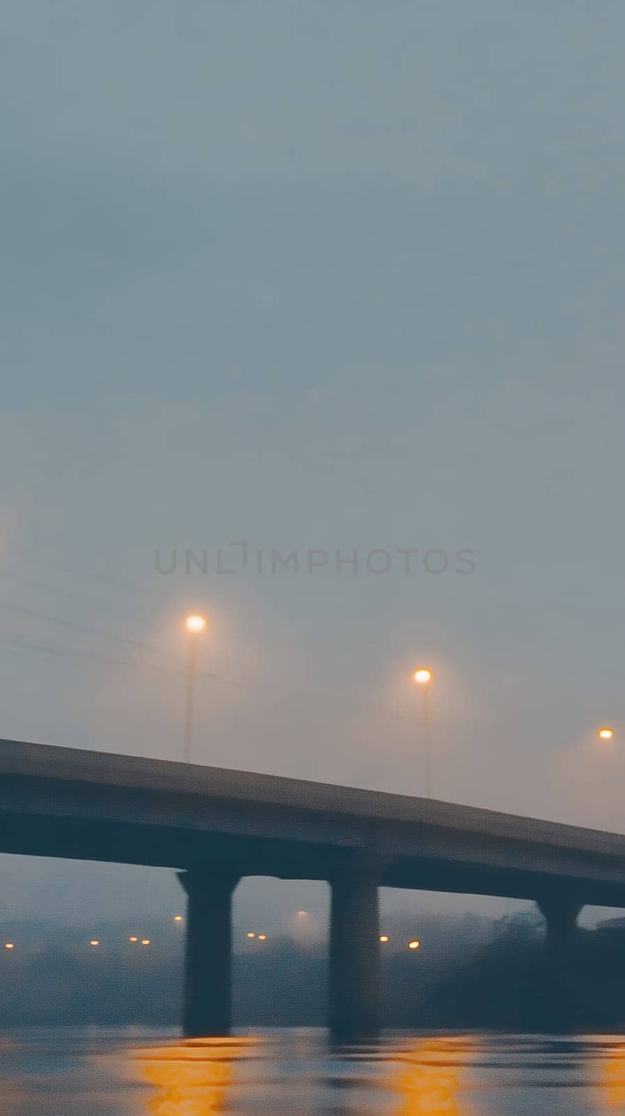 A bridge emerges from the fog, illuminated by streetlights, creating a mysterious and atmospheric night scene.