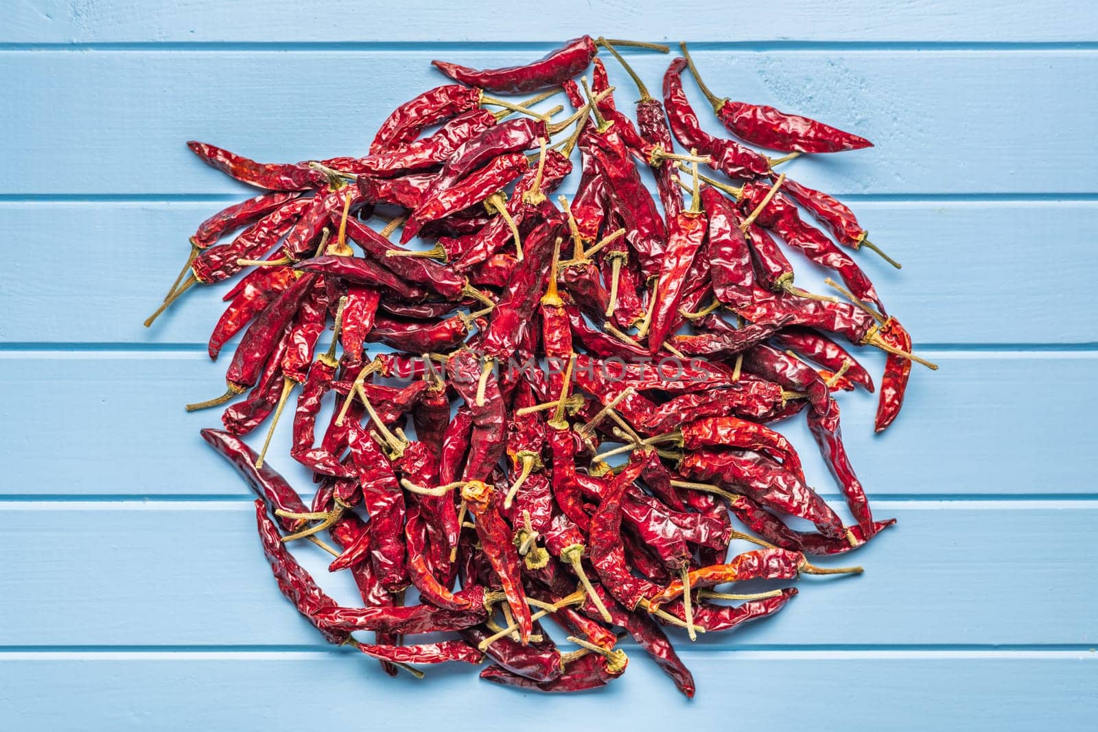 Dried red chili peppers on a blue table. Top view.