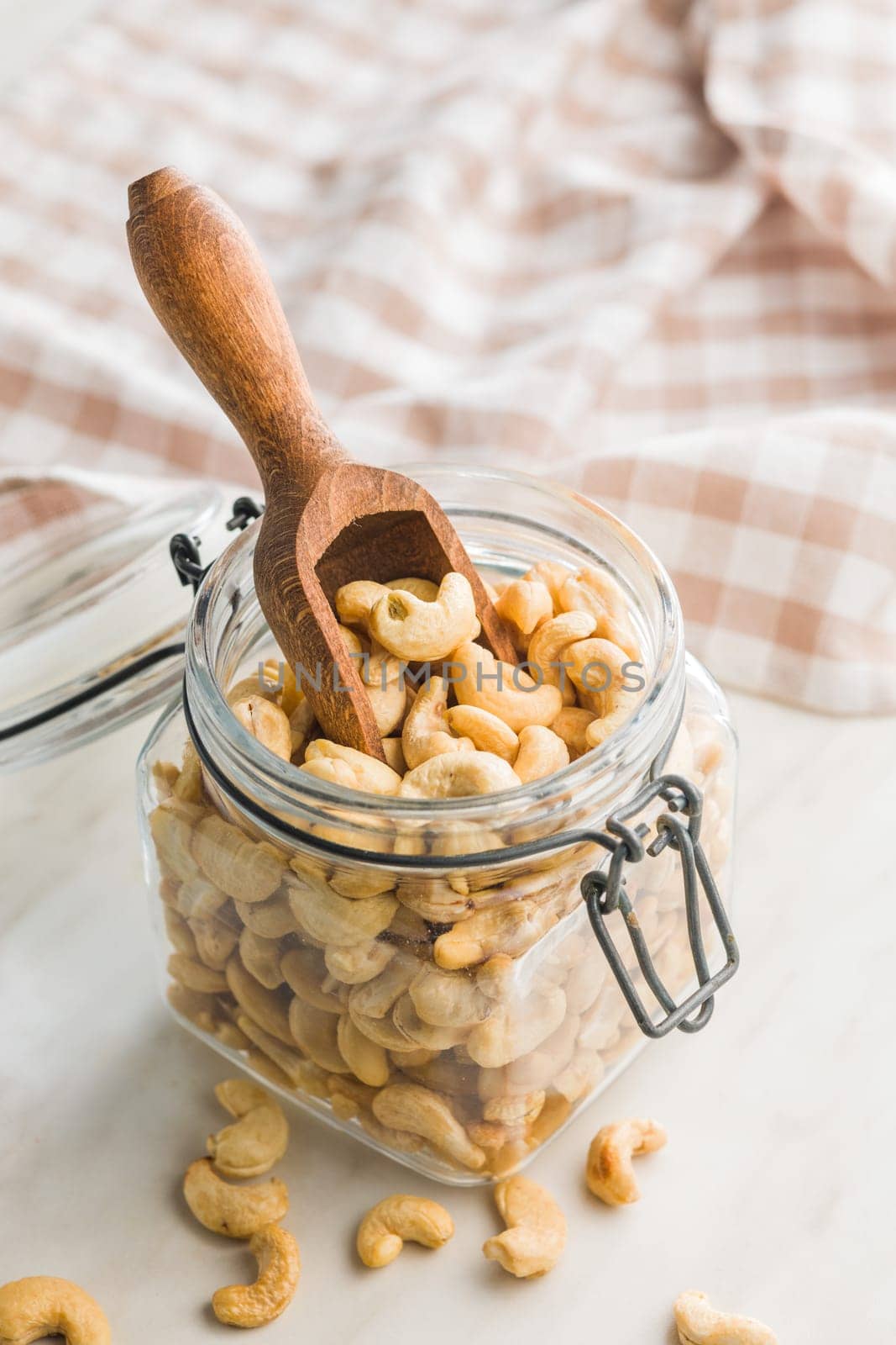 Roasted cashew nuts in jar on a kitchen table.