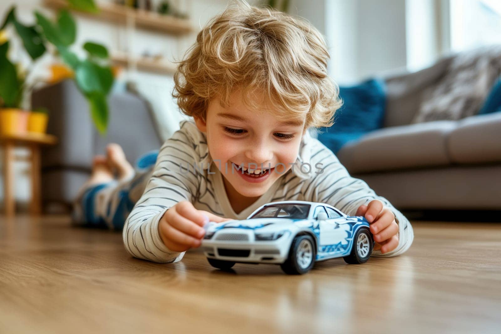 Smiling preschooler lying on the floor playing with a toy car at home