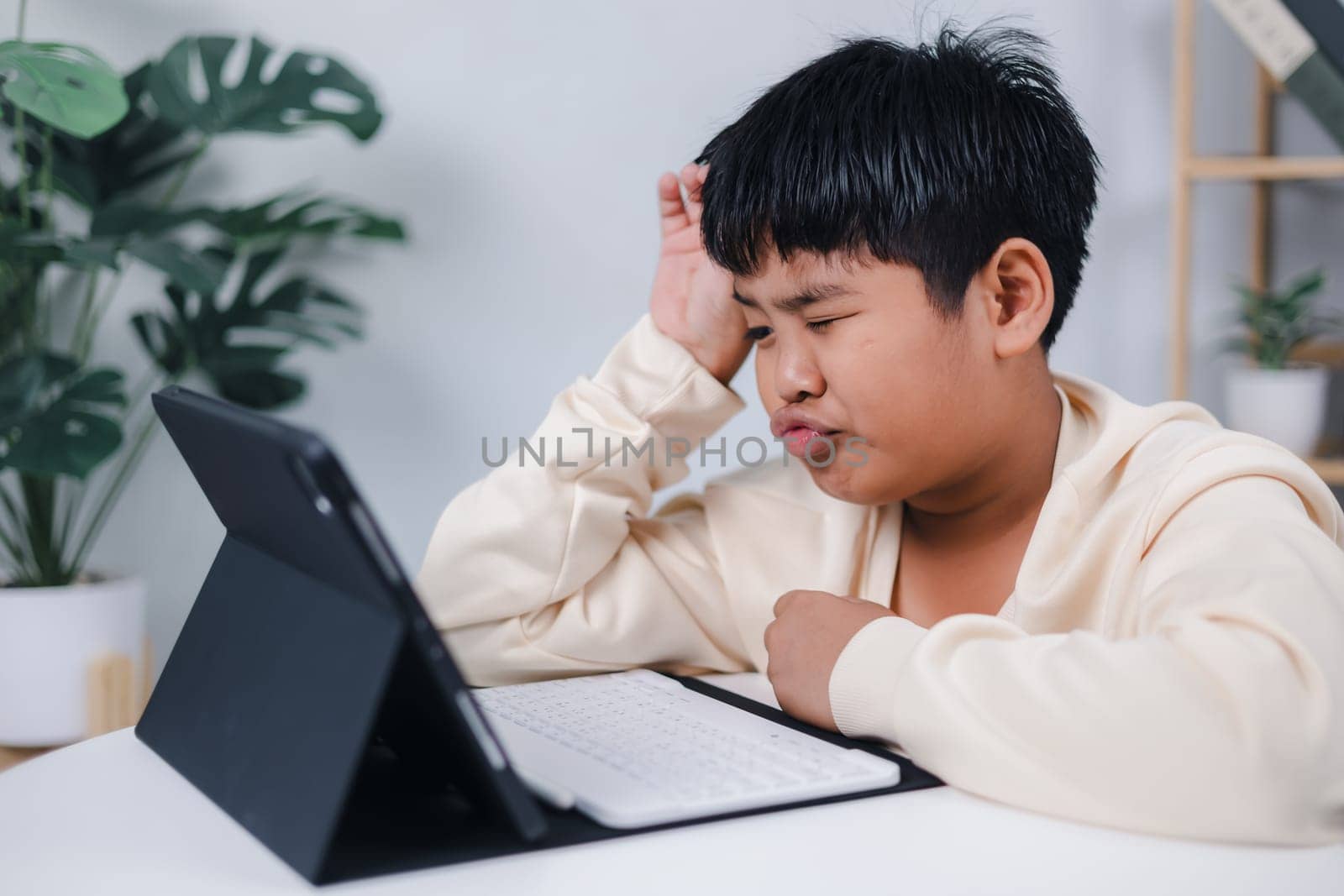 Boy using tablet for learning and stressed about online learning, Virtual internet online class from school teacher by remote meeting, Homeschooling and education concept, online education concept.