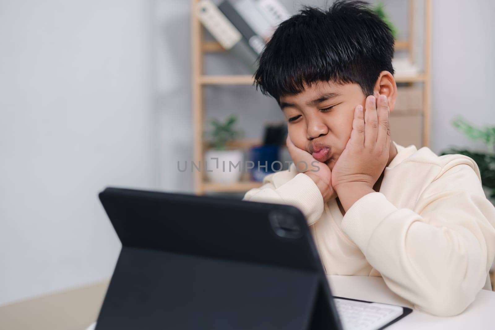 Boy using tablet for learning and stressed about online learning, Virtual internet online class from school teacher by remote meeting, Homeschooling and education concept, online education concept.