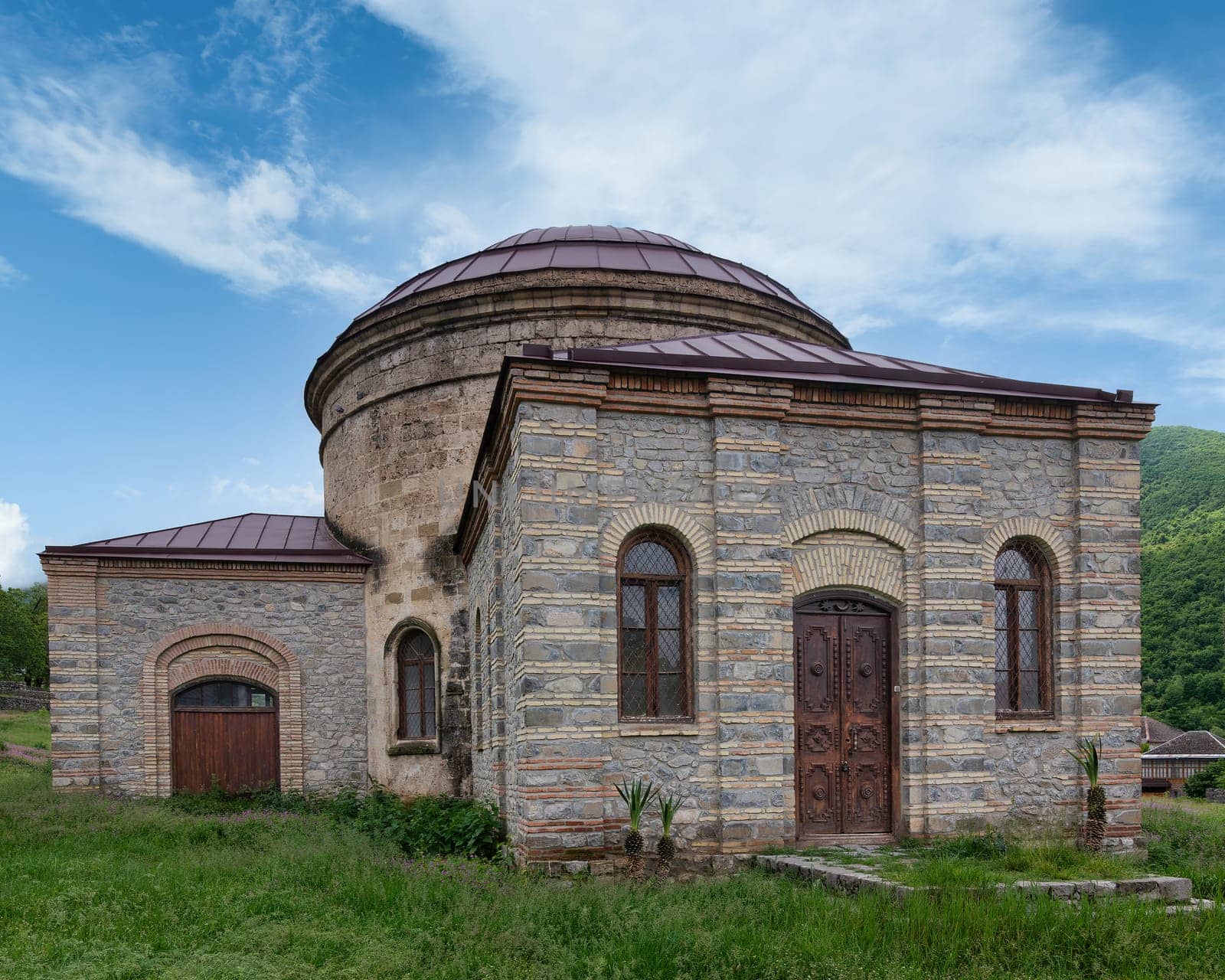 The Round Temple, also known as Three Saints Church, located near the Palace of Shaki Khans in Shaki, Azerbaijan, set against a backdrop of a clear blue sky