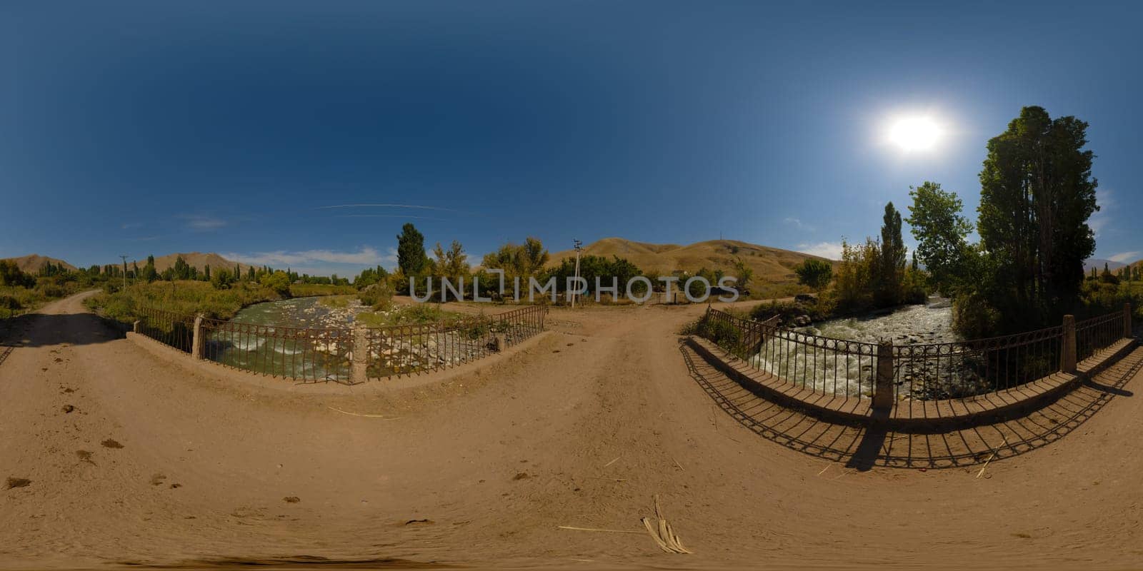 Full Spherical panorama of an old dusty bridge over mountain river at sunny autumn day in equirectangular projection. Blue sky with the sun in the sky.