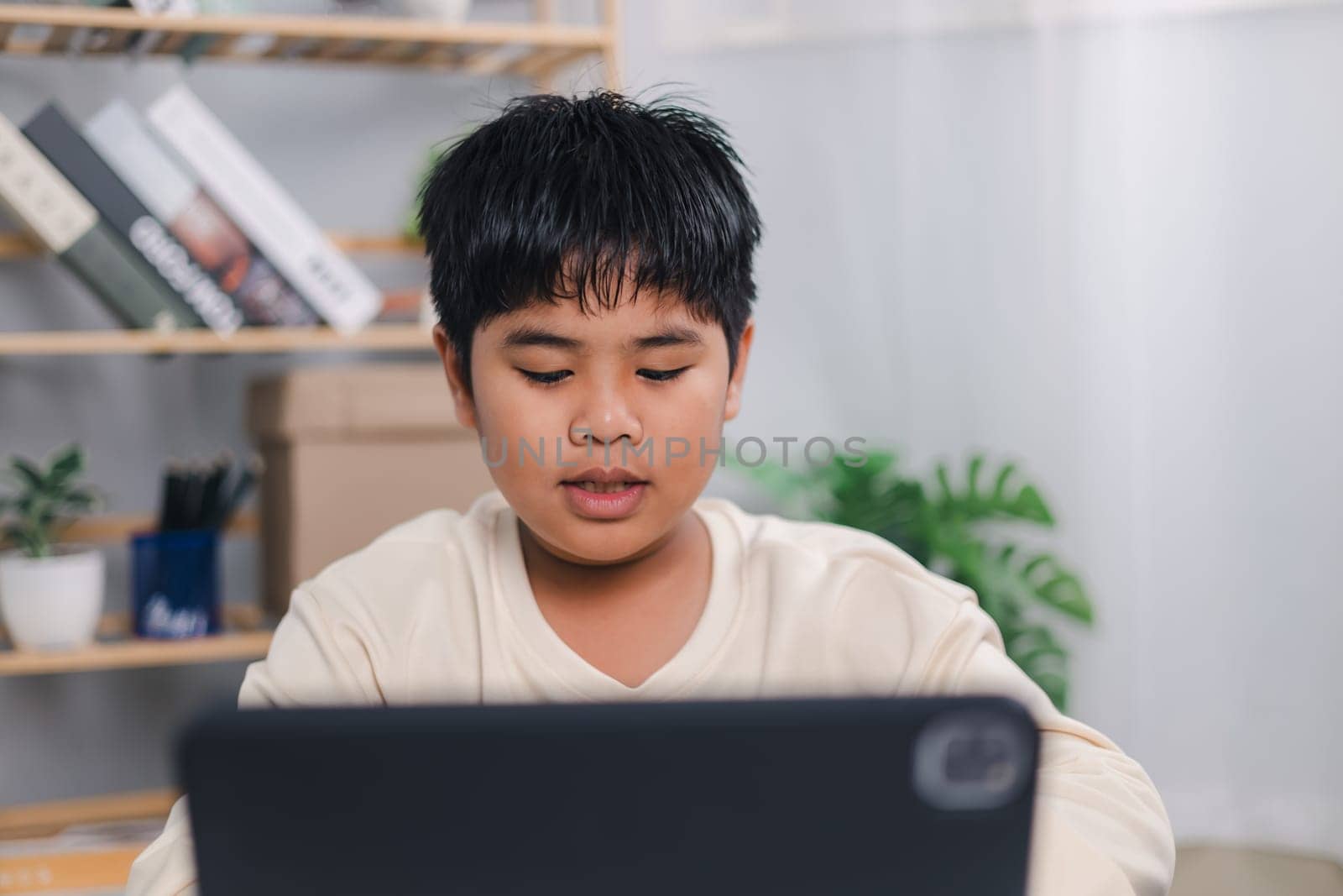 Asian boy student using tablet learning, Educational of tech concept, Staying at home, Presenting a modern educational way of life, Virtual internet online class from school teacher.