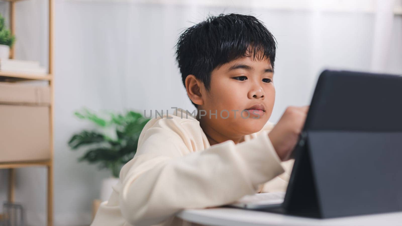 Asian boy student using tablet learning, Educational of tech concept, Staying at home, Presenting a modern educational way of life, Virtual internet online class from school teacher.
