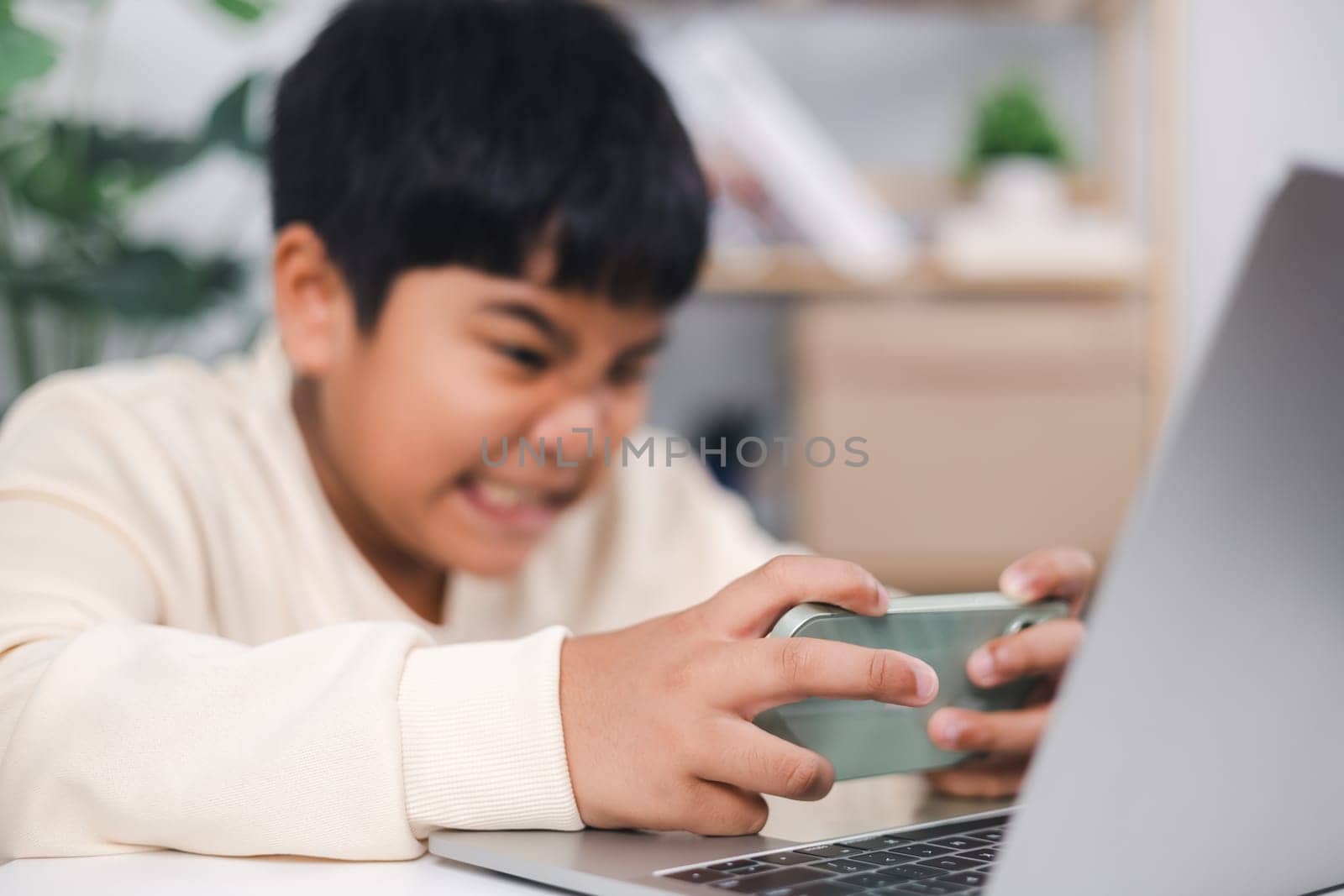 Getting serious asian boy using smartphone for playing mobile game Inside the house. Smartphone gaming online.