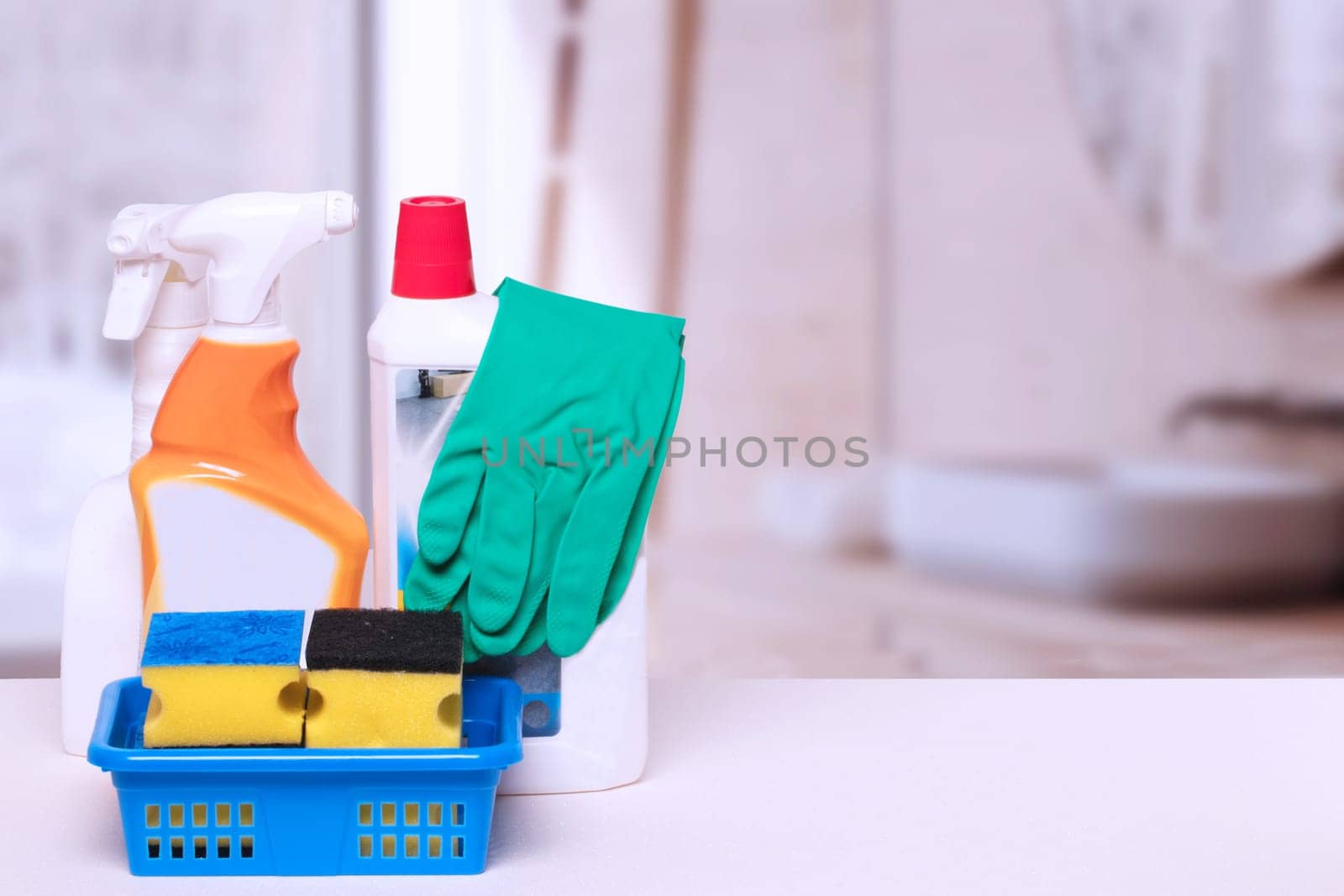 Household cleanliness and hygiene. Close-up of house cleaning products and cleaning supplies on a white table over abstract blurred bath background. Household chore concept. Macro.
