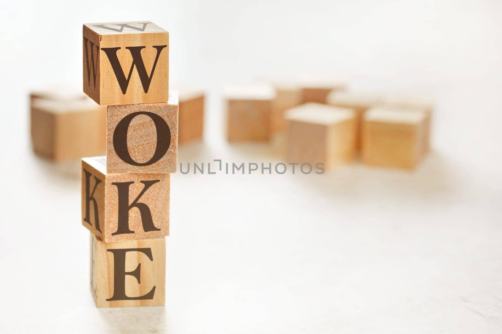 Four wooden cubes arranged in stack with word WOKE (stands for Wisdom Opportunity Knowledge and Empowerment) on them, space for text / image at down right corner