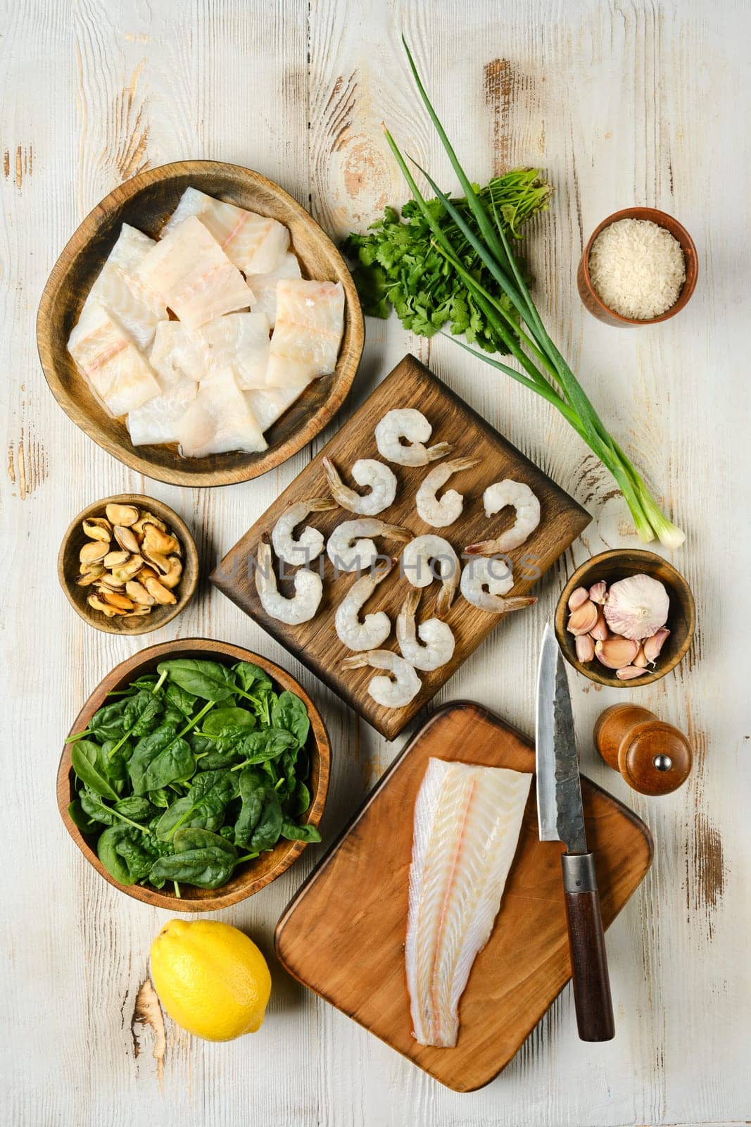 The kitchen countertop displays an assortment of fresh seafood and vibrant vegetables, including shrimp, fish fillets, and leafy greens, all set for a healthy meal preparation.