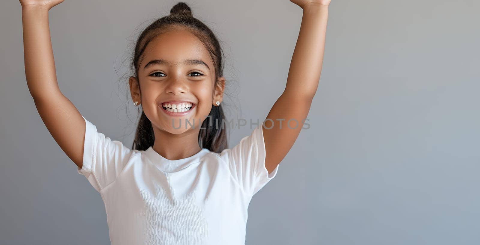 Portrait of a cheerful young girl celebrating with arms raised.