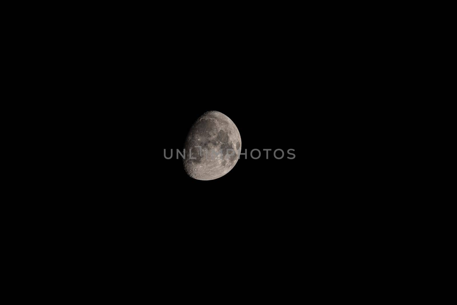 Nocturnal Glimpse: Telephoto Capture of Waning Moon.Telephoto lens reveals intricate details of the waning moon against a black nocturnal sky, emphasizing vast empty space
