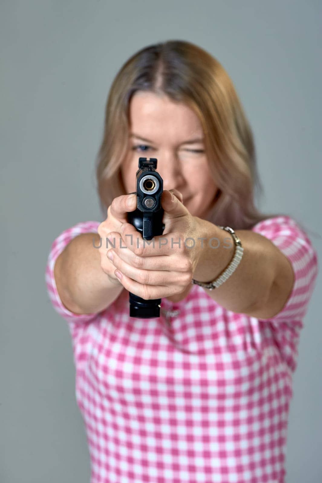 a beautiful woman aims a gun. High quality photo