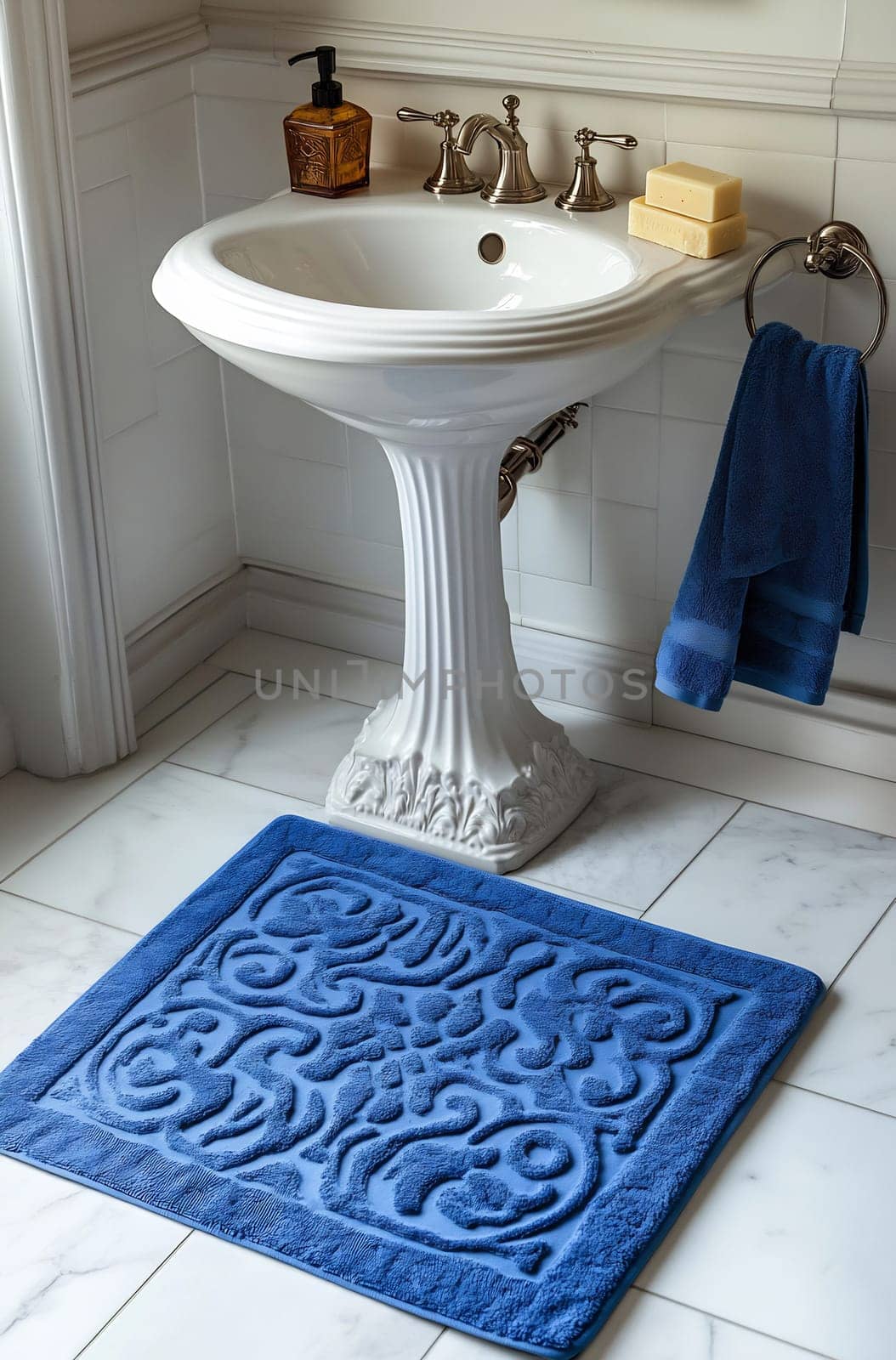 A beautifully designed bathroom features a white pedestal sink, blue rug, and towels, creating a serene and inviting atmosphere.