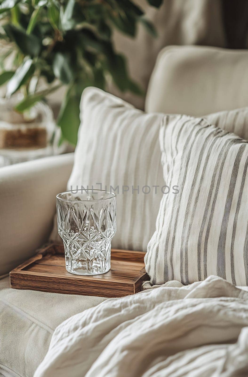 A beautifully styled living room features a glass on a wooden tray, surrounded by soft pillows and a warm atmosphere.