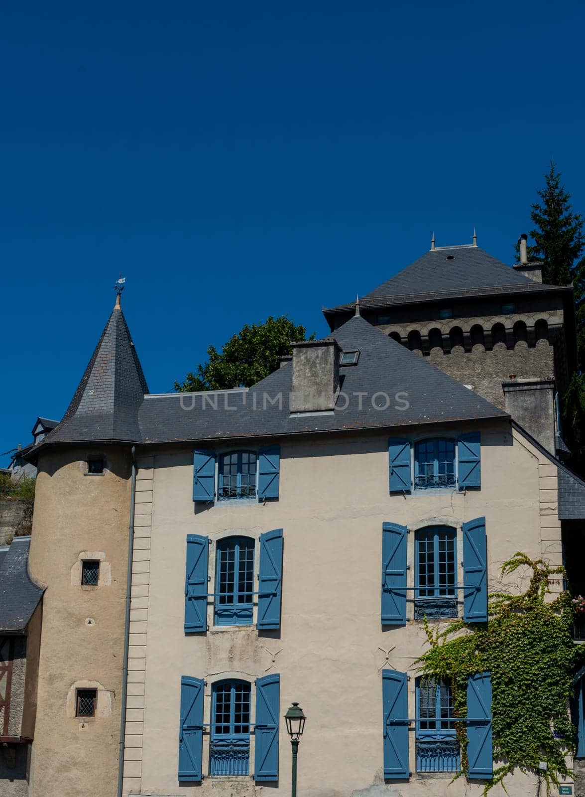 A building with blue shutters and a blue roof. The shutters are open and the building is tall