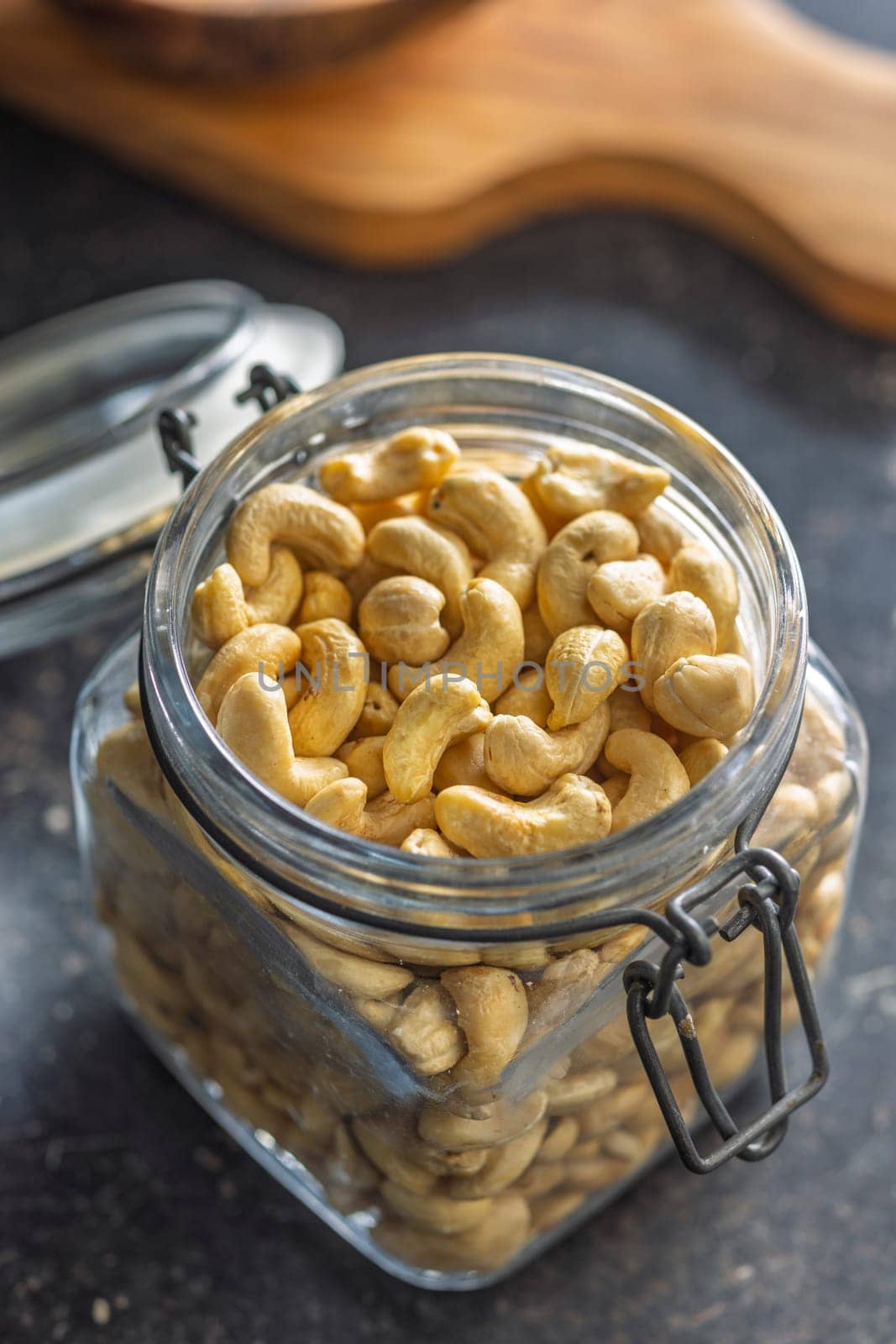 Roasted cashew nuts in jar on a black table.