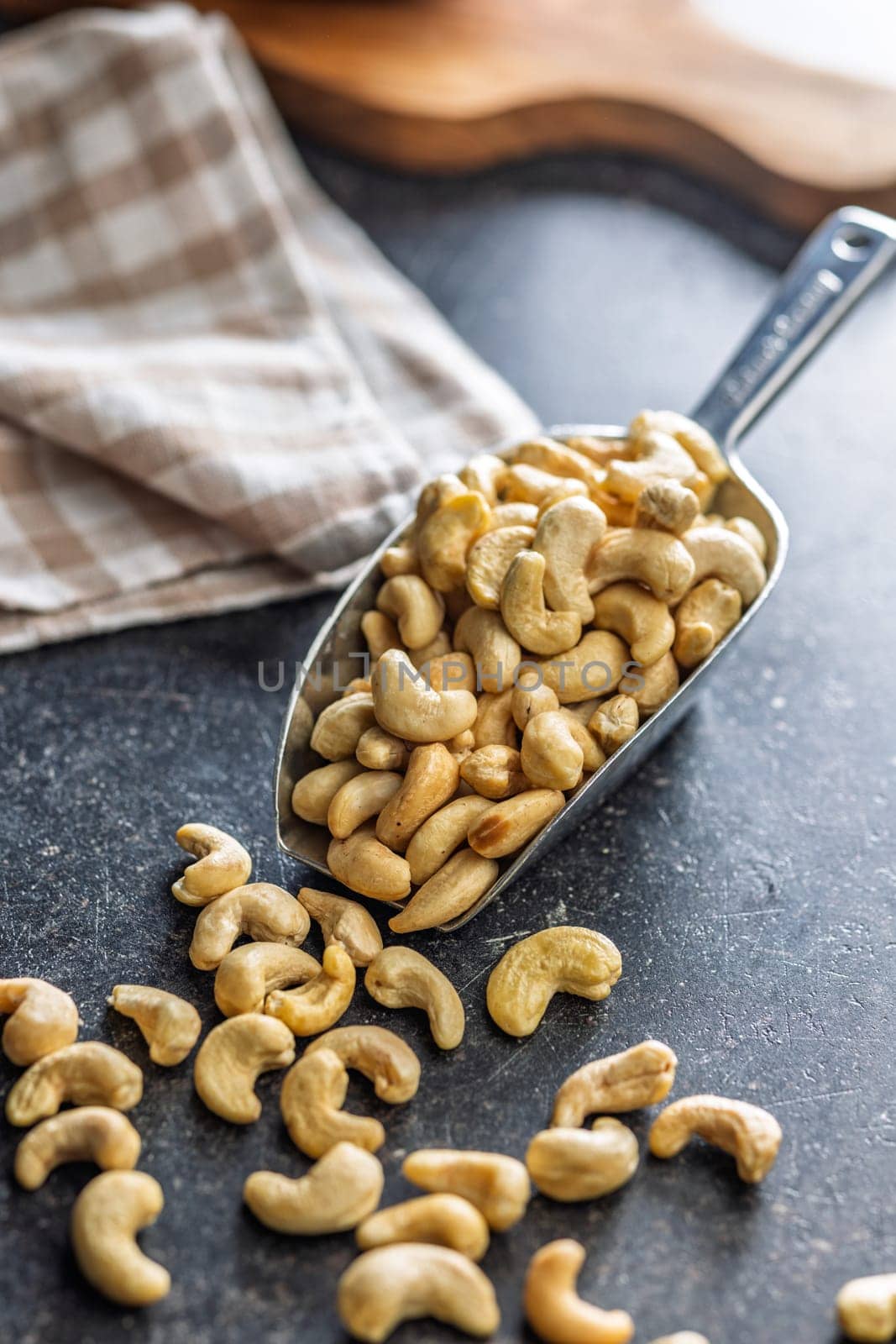 Roasted cashew nuts in scoop on a black table.