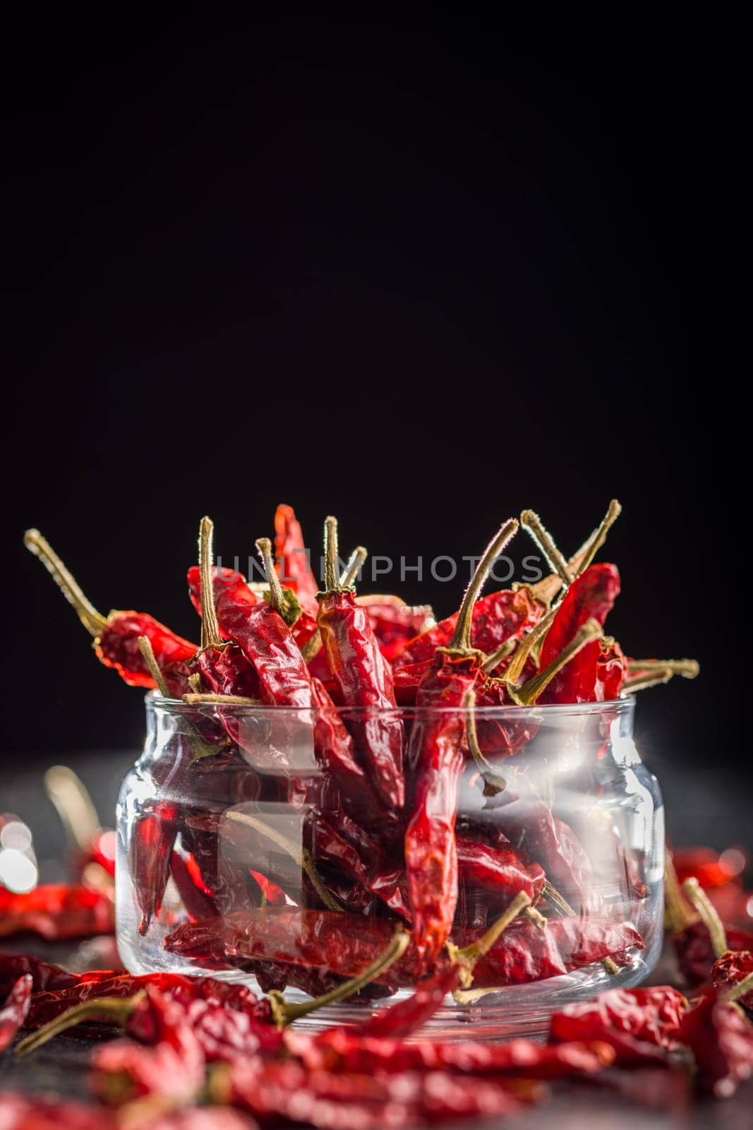 Dried red chili peppers in cup on a black table.