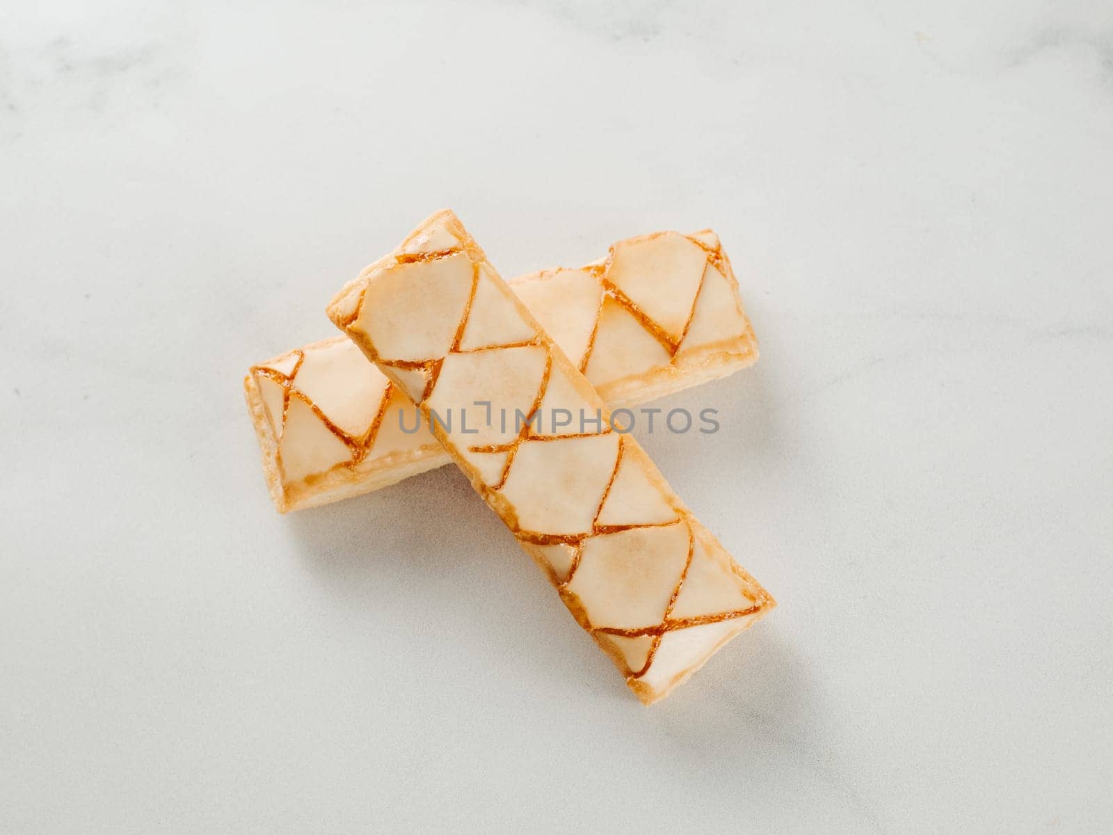 Italian crispy sweet bakery Sfogliatine glassate over white marble table surface. Tasty breakfast with apricot glaze puff pastries.