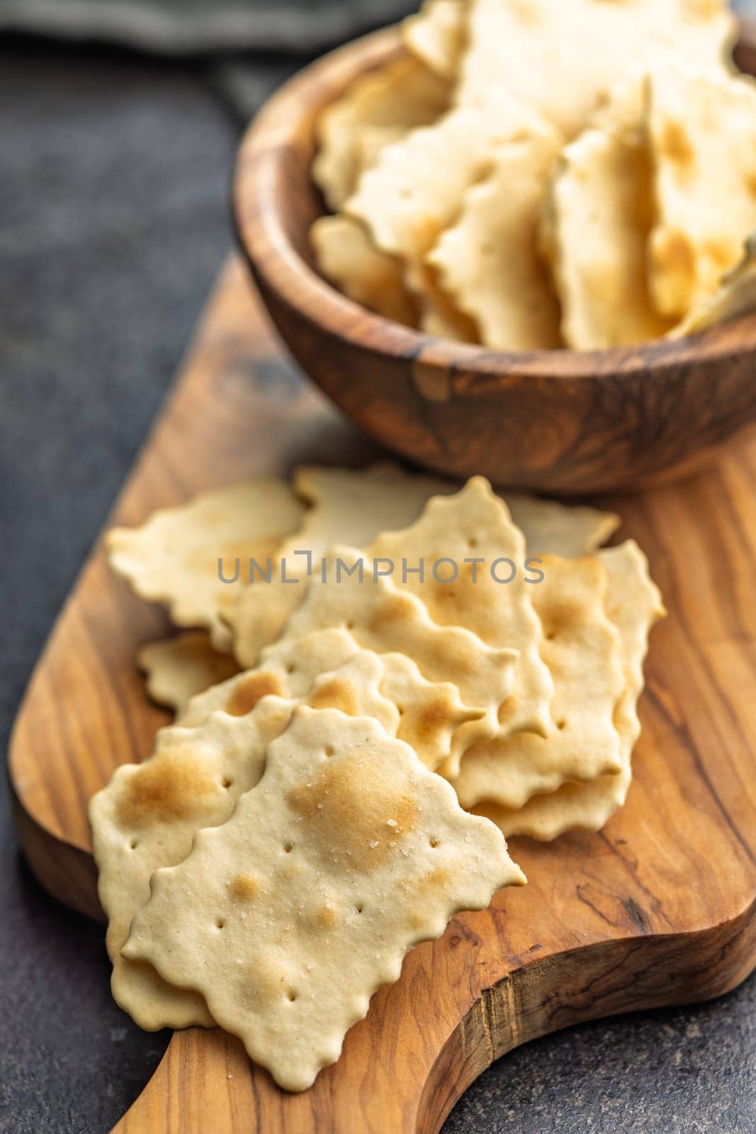 A crispy salted crackers on cutting board on a black table.