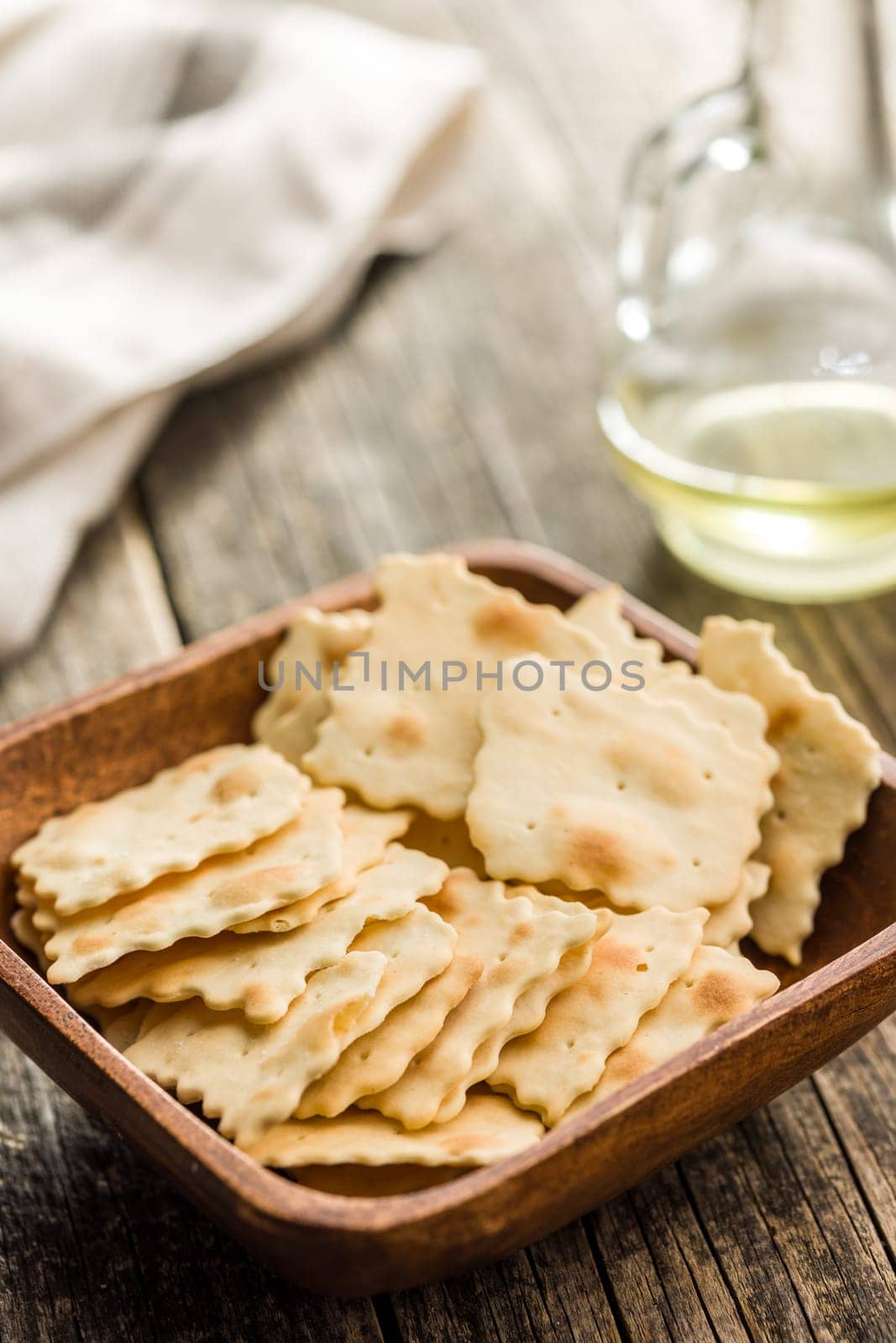A crispy salted crackers in bowl on a wooden table.