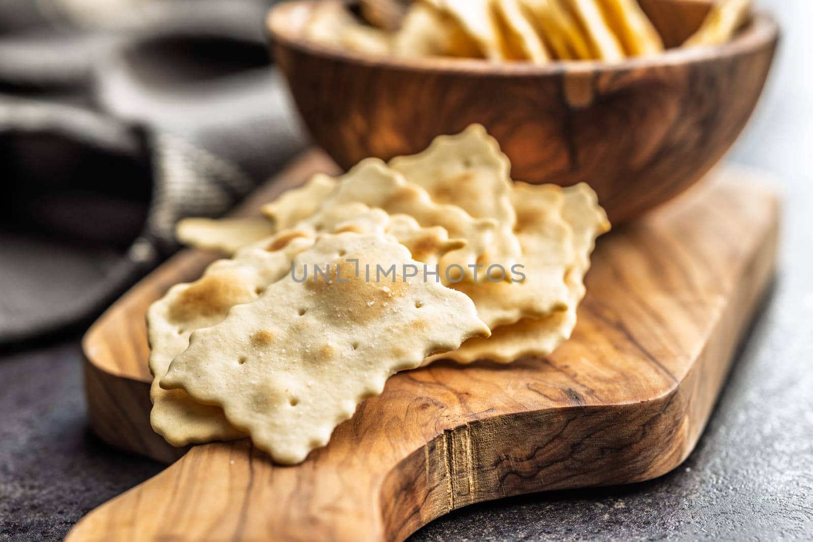 A crispy salted crackers on cutting board on a black table.