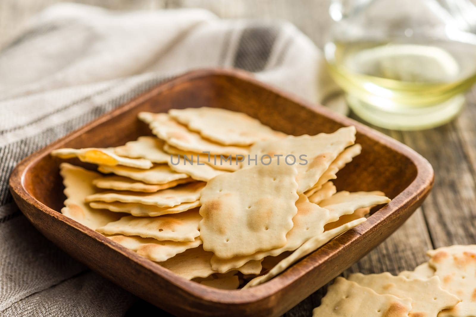 A crispy salted crackers in bowl on a wooden table.