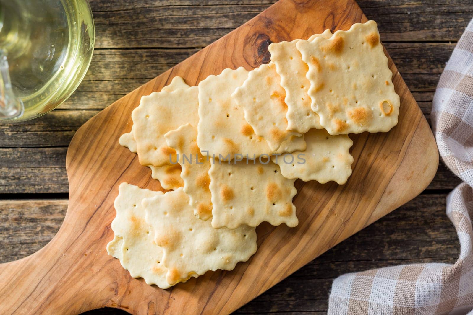 A crispy salted crackers on cutting board on a wooden table. Top view.