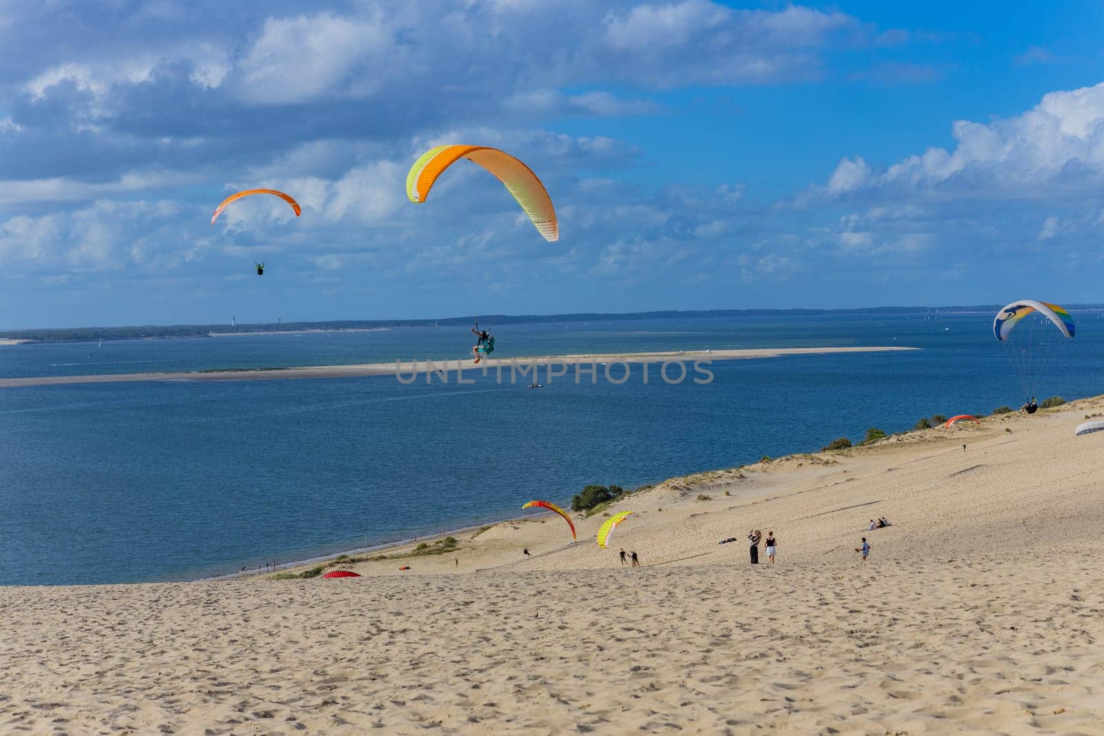 Dune of Pilat, France - August 14, 2024: People paragliding at the Great Dune of Pilat, Arcachon Basin, Nouvelle Aquitaine, France.