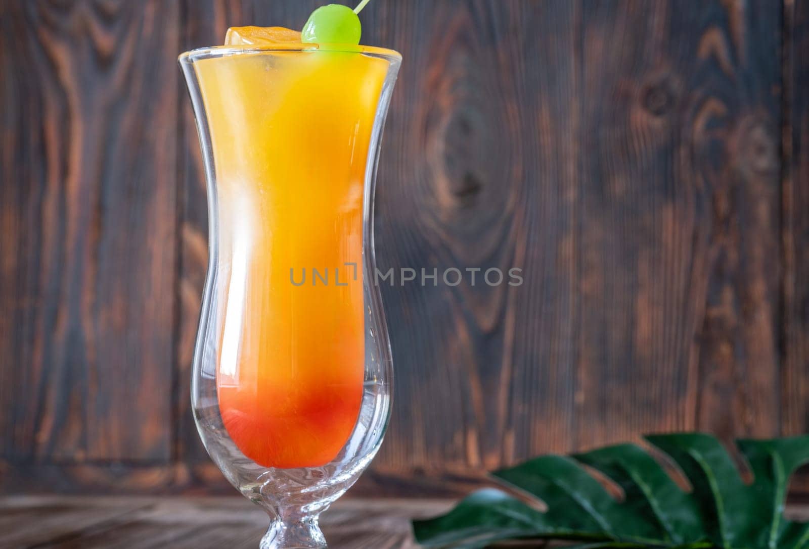 Banana Rum Punch cocktail garnished with green maraschino cherry